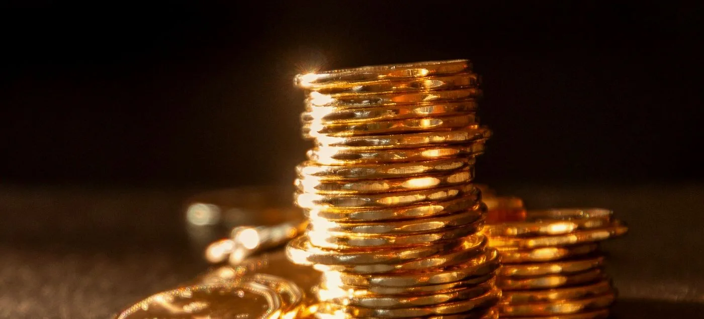 pile de pièces dorées éclairées dans la pénombre, symbolisant l'investissement et le budget d'un site web