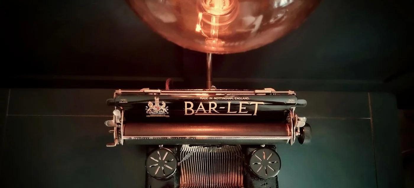 machine à écrire ancienne éclairée par une lampe chaude, symbolisant le choix de l'outil de publication adapté